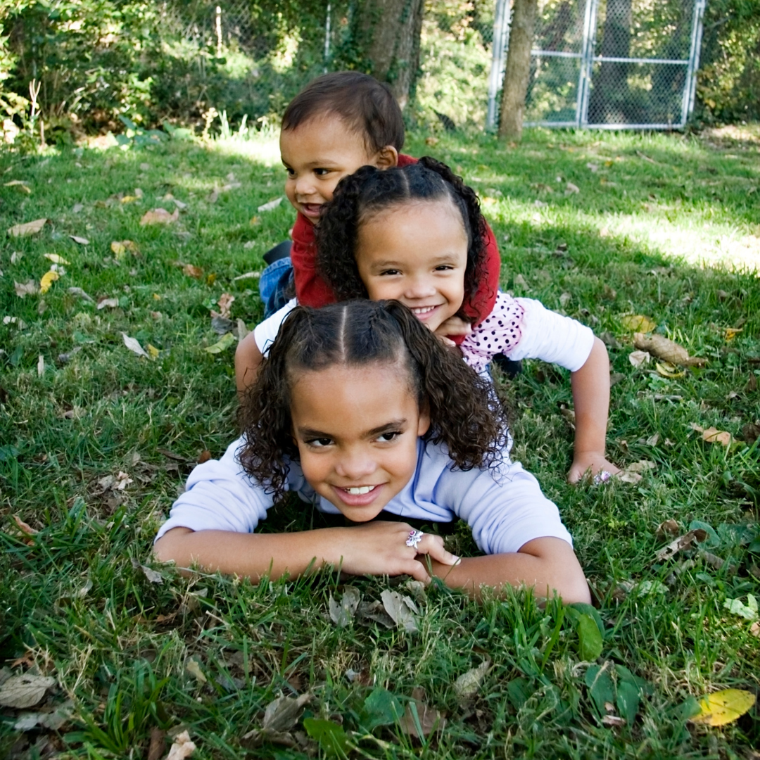 3 siblings lying on grass