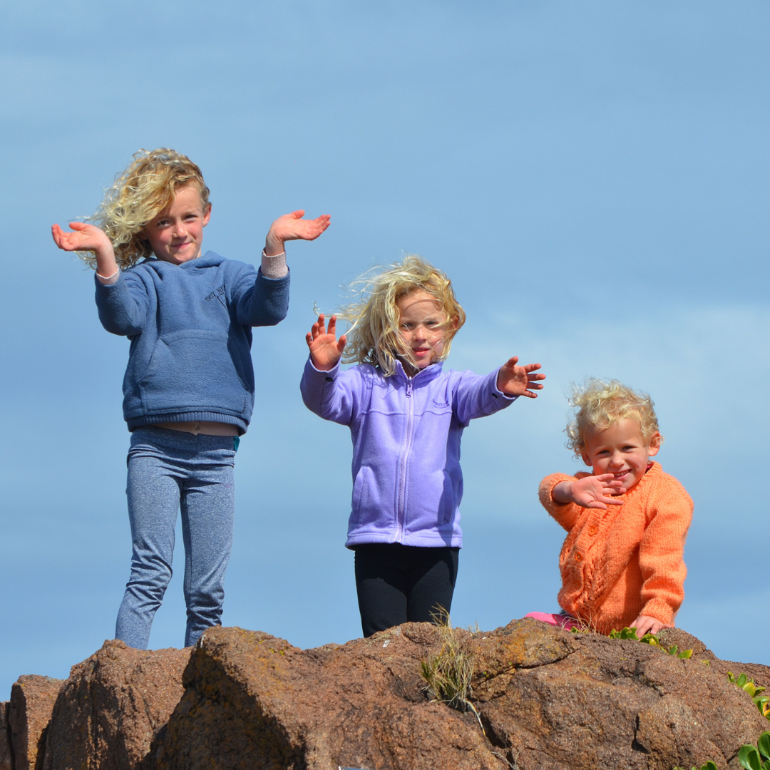 three siblings standing on a rock